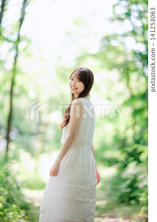一位身穿白色洋裝的女子,抓著裙擺大笑。 一位身穿白色洋裝的女子,抓著裙擺大笑。 141258063