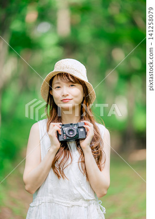 一位戴著草帽的女子麵帶微笑,手持相機。 一位戴著草帽的女子麵帶微笑,手持相機。 141258079