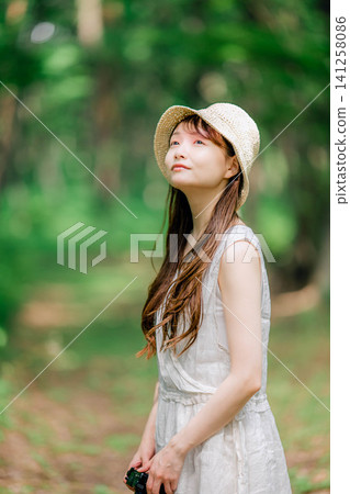 A woman in a straw hat smiles and looks up. A woman in a straw hat smiles and looks up. 141258086