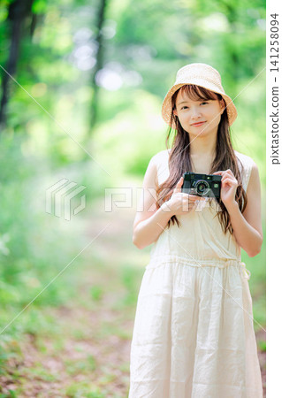 一位戴著草帽的女子手持相機走在街上,拍攝全身照。 一位戴著草帽的女子手持相機走在街上,拍攝全身照。 141258094