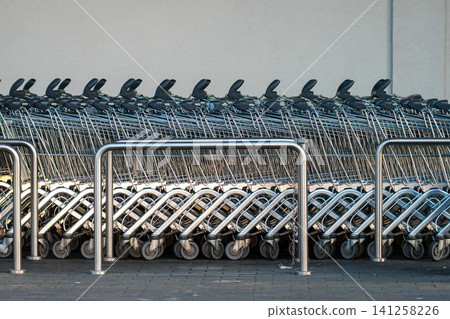 Rows of Shopping Carts Parked Outside Supermarket Entrance Ready for Customers Daily Use and Service Rows of Shopping Carts Parked Outside Supermarket Entrance Ready for Customers Daily Use and Service 141258226