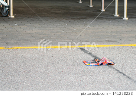 Discarded Advertising Brochure Outside Store Entrance Highlighting Wasteful Paper Consumption and Litter Discarded Advertising Brochure Outside Store Entrance Highlighting Wasteful Paper Consumption and Litter 141258228