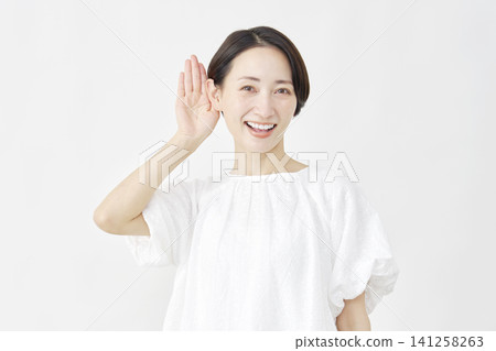 Middle-aged woman in a listening pose against a white background. Middle-aged woman in a listening pose against a white background. 141258263