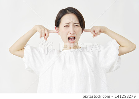 一位中年婦女摀著耳朵，背景是白色。 141258279