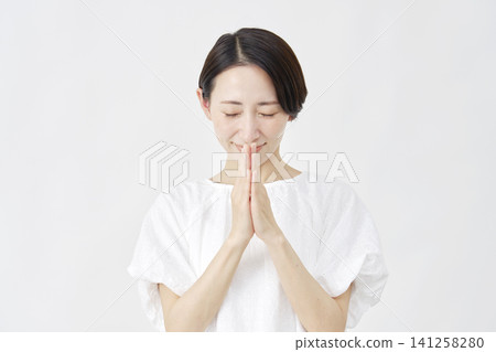 一位中年婦女在白色背景前祈禱。 141258280
