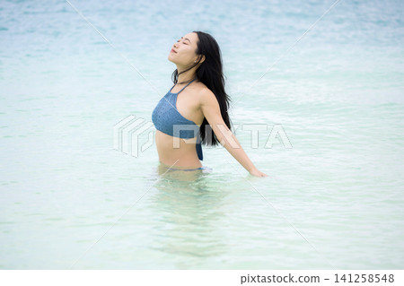 身穿泳衣的女子在沖繩海裡游泳 身穿泳衣的女子在沖繩海裡游泳 141258548