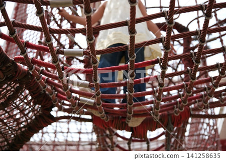Children playing on rope and net playground equipment in the park Children playing on rope and net playground equipment in the park 141258635