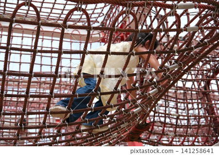Children playing on rope and net playground equipment in the park Children playing on rope and net playground equipment in the park 141258641
