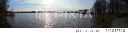 Wide angle panoramic image of sun shining over giant water body. Wide angle panoramic image of sun shining over giant water body. 141258818