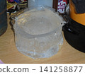 Ice block shaped by a bucket on wooden table, indoor close-up 141258877