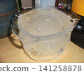 Bucket-shaped piece of ice with bubbles of air inside standing on a ktichen unit 141258878