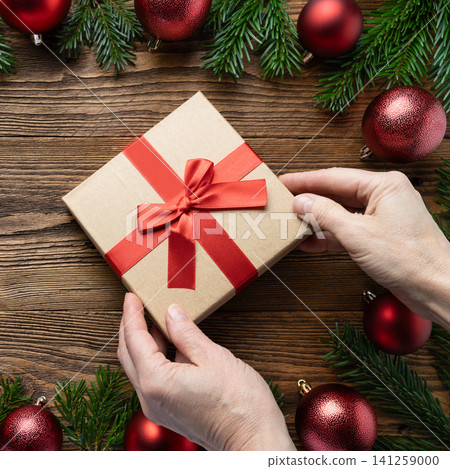 Hands holding Christmas gift box ribbon Hands holding Christmas gift box ribbon 141259000