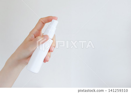 一雙女人的手拿著一瓶保養品。 一雙女人的手拿著一瓶保養品。 141259310