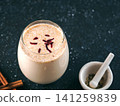 Traditional spiced milk beverage Sardai with saffron threads on top. Served in a glass on a dark background with mortar and cinnamon sticks. Copy space, perfect for Holi celebration marketing 141259839