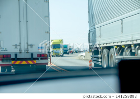 一輛普通轎車行駛在大型卡車之間的畫面 一輛普通轎車行駛在大型卡車之間的畫面 141259898