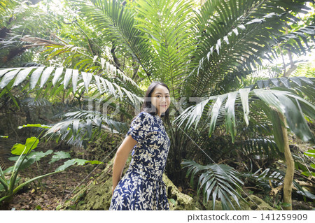 一位女子站在一片大葉子前──這是沖繩之旅的景象。 一位女子站在一片大葉子前──這是沖繩之旅的景象。 141259909