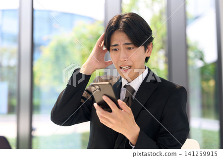 Businessmen who see annoying notifications on their smartphones Businessmen who see annoying notifications on their smartphones 141259915