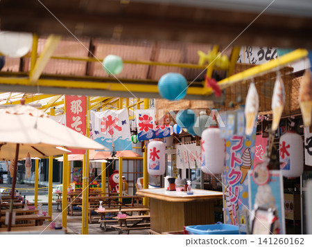 A Japanese summer scene: a retro rest stop lined with hanging banners advertising shaved ice and lanterns advertising soft serve ice cream. A Japanese summer scene: a retro rest stop lined with hanging banners advertising shaved ice and lanterns advertising soft serve ice cream. 141260162