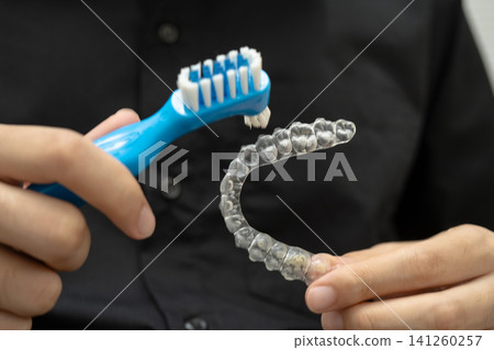 Man clean teeth brace removable retainer with brush. Man clean teeth brace removable retainer with brush. 141260257