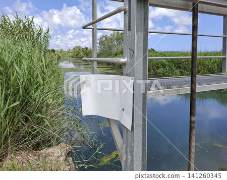 A steel water control structure is shown alongside a depth gauge plate in the irrigation canal. This scene is from the organic Bomba rice cultivation zone in Pego. A steel water control structure is shown alongside a depth gauge plate in the irrigation canal. This scene is from the organic Bomba rice cultivation zone in Pego. 141260345