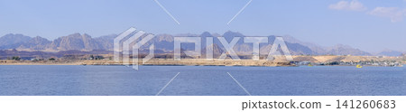 Panoramic landscape featuring mountains and coastline by the Red Sea in Egypt, with a clear blue sky and tranquil water enhancing the scenery Panoramic landscape featuring mountains and coastline by the Red Sea in Egypt, with a clear blue sky and tranquil water enhancing the scenery 141260683