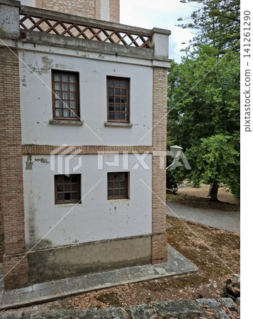 The image shows a corner of a two story building with brick trim. The windows are broken and the area is overgrown. This is part of the abandoned San Francisco de Borja sanatorium complex. The image shows a corner of a two story building with brick trim. The windows are broken and the area is overgrown. This is part of the abandoned San Francisco de Borja sanatorium complex. 141261290