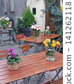Outdoor Cafe Tables With Fresh Flower Arrangements On Wooden Bistro Tables In Charming Courtyard 141262118