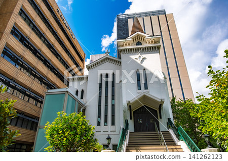 Yokohama Kaigan Church, a historic white building standing against a backdrop of modern skyscrapers in Yokohama City, Kanagawa Prefecture. Yokohama Kaigan Church, a historic white building standing against a backdrop of modern skyscrapers in Yokohama City, Kanagawa Prefecture. 141262123