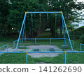 A swing at dusk, surrounded by trees 141262690