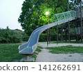 A roller slide and streetlights in a park at dusk 141262691