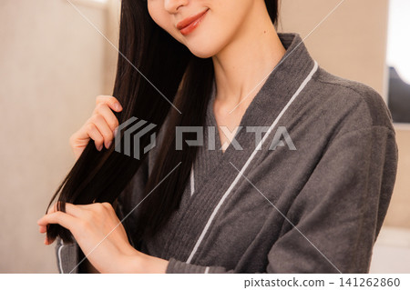 A woman doing hair care in the bathroom A woman doing hair care in the bathroom 141262860