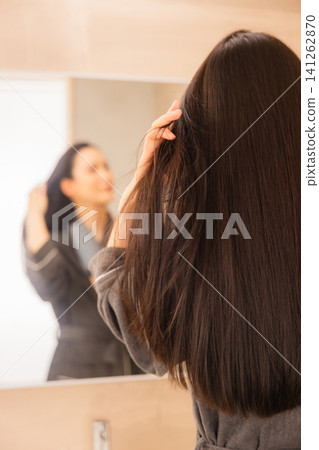 A woman doing hair care in the bathroom 141262870