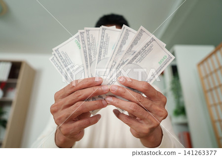 Close up of hands holding fan of one hundred dollar bills 141263377