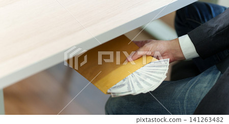 Cropped hand passing envelope with money under desk for bribery concept Cropped hand passing envelope with money under desk for bribery concept 141263482