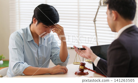 Stressed Asian man receiving legal advice from lawyer in office Stressed Asian man receiving legal advice from lawyer in office 141263505