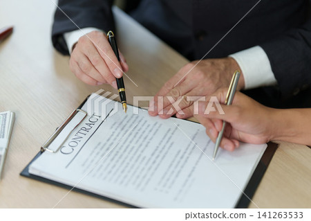 Close up of business partners signing contract agreement on desk 141263533