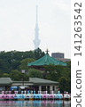 Colorful swan boats lined up on Shinobazu Pond in Ueno Park, along with Bentendo Temple, and the Tokyo Skytree shrouded in mist in the background. 141263542