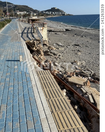 Damaged seaside promenade with crumbled pavement and exposed rocks on a sunny day Damaged seaside promenade with crumbled pavement and exposed rocks on a sunny day 141263839