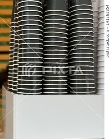 Stacks of disposable coffee cups in holder against colorful striped wall, available as background Stacks of disposable coffee cups in holder against colorful striped wall, available as background 141263854