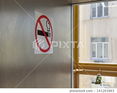 No smoking sign on a wall in a building, daylight streaming through nearby window No smoking sign on a wall in a building, daylight streaming through nearby window 141263863