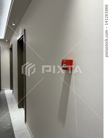 Fire alarm on white ceiling in modern building interior with natural light from windows 141263866