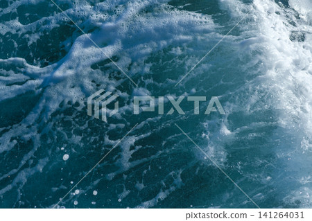 Close-up of ocean waves displaying white foam and deep blue water, illustrating the dynamic texture and movement of the sea surface Close-up of ocean waves displaying white foam and deep blue water, illustrating the dynamic texture and movement of the sea surface 141264031