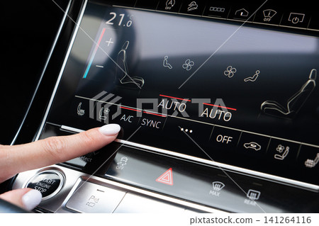Woman finger pressing AC button on car touch screen climate control system Woman finger pressing AC button on car touch screen climate control system 141264116
