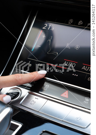 Woman finger pressing AC button on car touch screen climate control system Woman finger pressing AC button on car touch screen climate control system 141264117