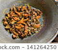A close-up of chopped chicken including chicken feet being simmered and seasoned with soy sauce in a large metal wok. Traditional Asian cooking style, local cuisine, and food preparation 141264250