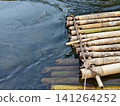 A top view of a traditional handmade bamboo raft tied with rope, floating on clear river water. Perfect for eco-tourism, outdoor adventure, tropical travel, and nature background concepts. 141264252