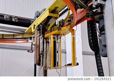 Close up view of automated industrial rotary stretch wrapping machine mechanism with yellow carriage Close up view of automated industrial rotary stretch wrapping machine mechanism with yellow carriage 141264521