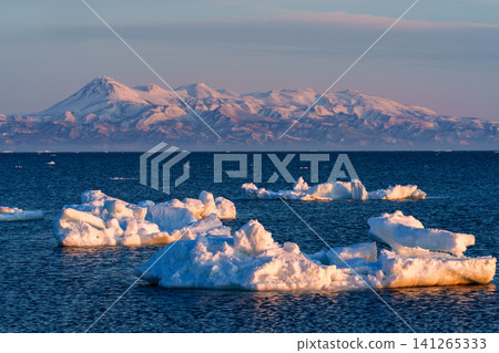 A stunning winter landscape of drift ice illuminated by the morning light, with the Shiretoko mountain range, including Mount Rausu, as seen from the Notsuke Peninsula in Hokkaido. A stunning winter landscape of drift ice illuminated by the morning light, with the Shiretoko mountain range, including Mount Rausu, as seen from the Notsuke Peninsula in Hokkaido. 141265333