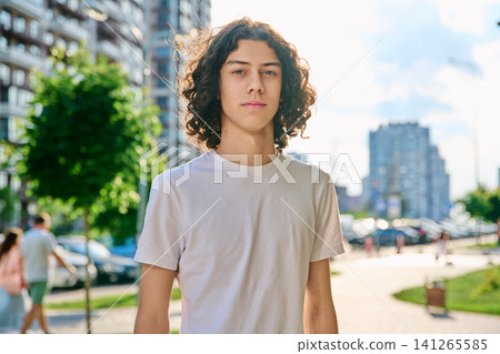 Portrait of confident teenage boy with curly hair outdoors Portrait of confident teenage boy with curly hair outdoors 141265585