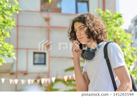 Curly teen student talking on phone near campus Curly teen student talking on phone near campus 141265594